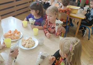 dzieci siedzą przy stolikach i jedzą popcorndzieci siedzą przy stolikach i jedzą popcorn