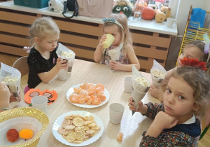 dzieci siedzą przy stolikach i jedzą popcorn