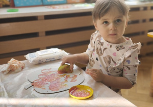 dziewczynka stempluje stempelkiem z jabłka