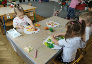 dziewczynki stemplują stempelkami z połówki jabłka