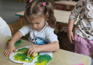 dziewczynka stempluje połówką jabłka