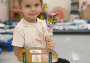 dziewczynka z lizakiem siedzi na krzesełku