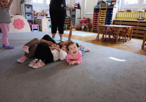 dzieci leżą na wykładzinie pod chusta animacyjną