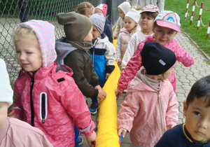 dzieci idą przy zabawkowym wężu na spacer