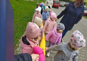 dzieci idą przy zabawkowym wężu na spacer