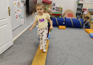 dziewczynka pokonuje tor przeszkód po ławeczce