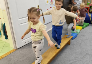 dzieci pokonują tor przeszkód po ławeczce