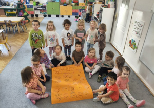 dzieci siedzą wokół plakatu z podziękowaniami dla seniorów
