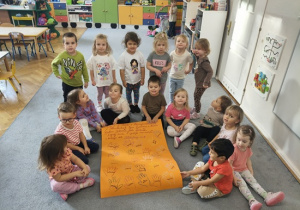 dzieci siedzą wokół plakatu z podziękowaniami dla seniorów