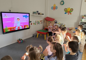 grupa dzieci pokazuje to samo co postać w telewizorze