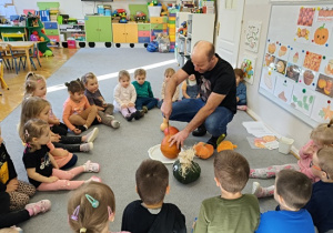 Pan Marcin kroi dynię a dzieci siedzą w kole i obserwują