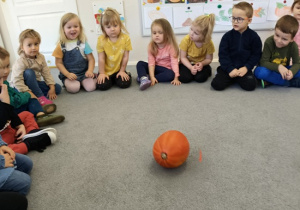 dzieci siedzą wokół dyni