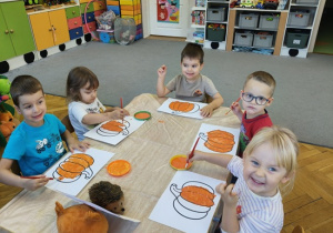 dzieci malują pędzlami kontur dyni
