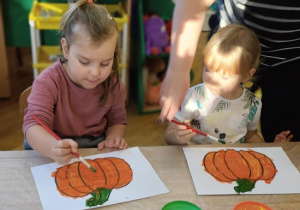 dzieci malują pędzlami kontur dyni