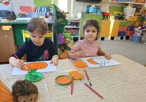 dzieci malują pędzlami kontur dyni