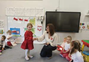 Pani Ewa wręcza dziewczynce książkę i dyplom