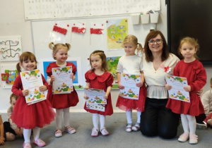 dziewczynki z Panią Ewą , książkami i dyplomami pozują do zdjęcia