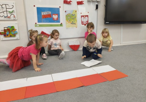dzieci układają na podłodze flagę biało- czerwoną