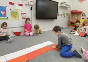 dzieci układają na podłodze flagę biało- czerwoną