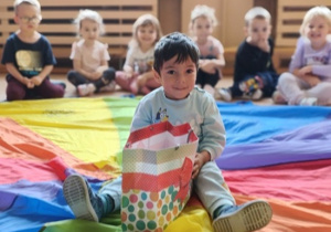 chłopiec siedzi na kolorowej chuście z torbą cukierków