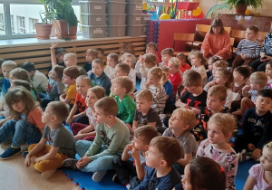 dzieci siedzą na materacu i słuchają Pani leśnik