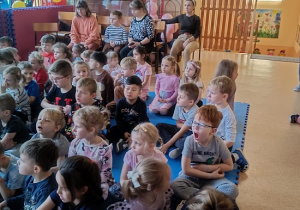 dzieci siedzą na materacu i słuchają Pani leśnik