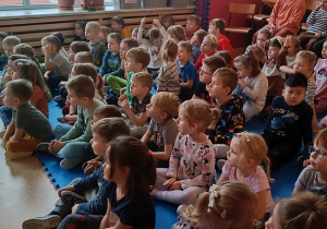 dzieci siedzą na materacu i słuchają Pani leśnik
