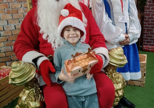 chłopiec z prezentem w obecności Mikołaja i śnieżynki