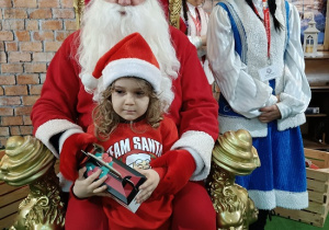 chłopiec z prezentem w obecności Mikołaja i śnieżynki