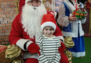 chłopiec z prezentem w obecności Mikołaja i śnieżynki