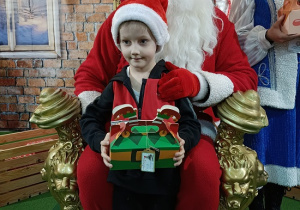 chłopiec z prezentem w obecności Mikołaja i śnieżynki