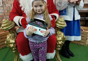 dziewczynka z prezentem w obecności Mikołaja