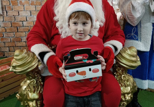 chłopiec z prezentem w obecności Mikołaja i Śnieżynki