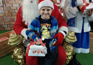 chłopiec z prezentem w obecności Mikołaja i Śnieżynki