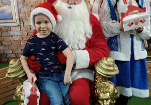chłopiec z prezentem w obecności Mikołaja i Śnieżynki