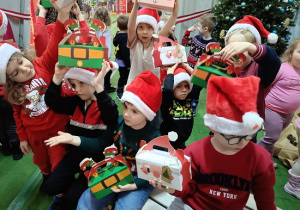 dzieci z prezentami w czapkach mikołajkowych