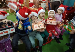 dzieci z prezentami w czapkach mikołajkowych