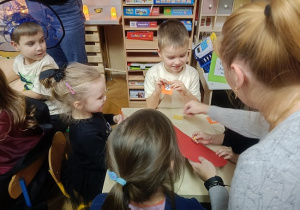 dzieci wróżą sobie przebijając szpilką papierowe serce