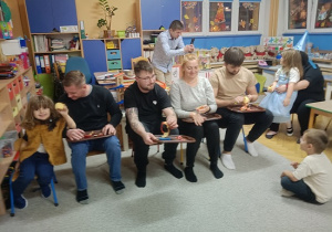 rodzice siedzą na krzesełkach i obierają skórkę jabłka