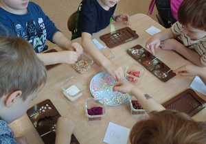 dzieci dekorują czekoladowe lizaki