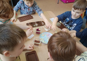 dzieci dekorują czekoladowe lizaki
