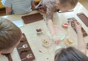 dzieci dekorują czekoladowe lizaki