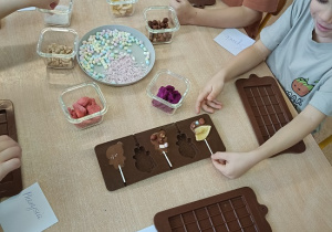 dzieci dekorują czekoladowe lizaki