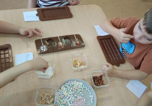 dzieci dekorują czekoladowe lizaki