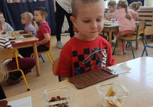 chłopiec z uwagą przygotowuje się do dekorowania czekolady