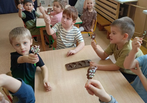 dzieci pokazują swoje udekorowane czekoladowe lizaki