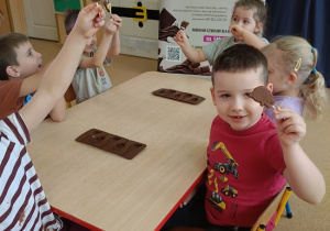 dzieci pokazują swoje udekorowane czekoladowe lizaki