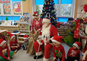 Mikołaj i śnieżynki rozdają dzieciom prezenty