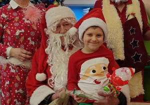 chłopiec z prezentem siedzi na kolanach Mikołaja