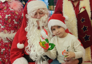 chłopiec z prezentem siedzi na kolanach Mikołaja